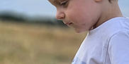 Noé a rejoint le concours — aidez-le/la à gagner de superbes lots ! child, toddler, boy, side_profile, white_tshirt, bird_print, outdoor, field, grass, nature, sky, cloudy, portrait, casual_clothing, young_child, curly_hair, daytime, innocence, peaceful, candid