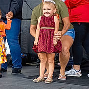 Aubrey is registered to the contest to win money with this photo: child, girl, woman, tiara, dress, smile, stage, event, people, footwear, microphone, casual_clothing, jeans, shorts, supporting_hand, happy, portrait, indoor, celebration, crowd
