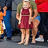 child, girl, woman, tiara, dress, smile, stage, event, people, footwear, microphone, casual_clothing, jeans, shorts, supporting_hand, happy, portrait, indoor, celebration, crowd