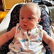 Nino participe au concours pour gagner de l'argent avec cette photo : baby, child, clothing, colorful, comfort, curious, cute, expression, face, floral_skirt, indoor, infant, lap, patterned_clothes, person, shorts, sitting, skin, sleeveless, wood_floor