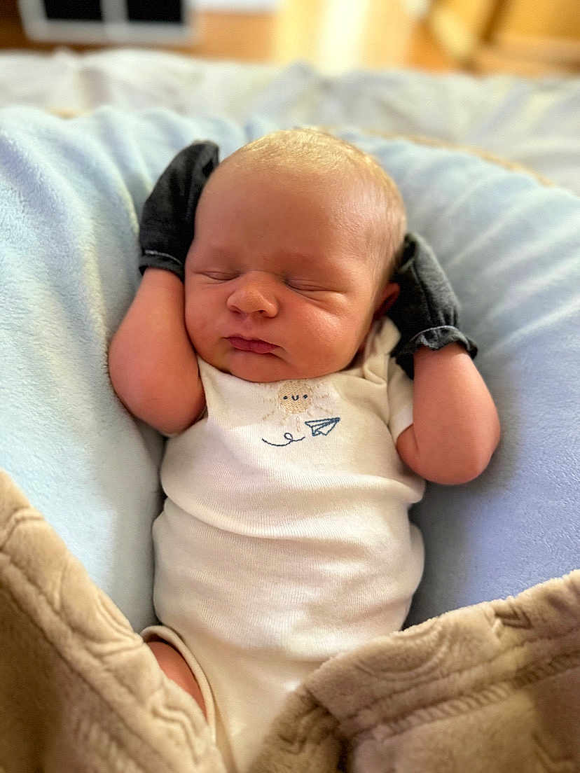 Clayton is registered to the contest to win money with this photo: baby, newborn, sleeping, mittens, blanket, cushion, infant, cozy, comfort, soft, white_onesie, peaceful, cute, resting, indoor, portrait, human, child, closeup, relaxation