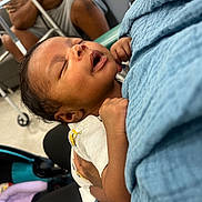 Asiah is registered to the contest to win money with this photo: baby, sleeping, blanket, arms, person, clothing, indoor, stroller, seated, adult, hand, comfort, rest, toddler, care, closeup, face, holding, soft, peaceful