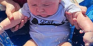 Bryson is registered to the contest to win money with this photo: baby, water, splash, outdoor, adult, hand, arm, clothing, necklace, sunlight, pool, blue, skin, tattoo, person, summer, feet, playing, expression, parent