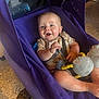 Bryson is registered to the contest to win money with this photo: baby, child, stroller, purple, smiling, toy, plush_toy, infant, clothing, indoor, seat_belt, happy, face, person, footwear, floor, fabric, casual, comfort, expression