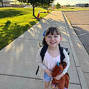 Katie Gardner joined the competition — help win amazing prizes! backpack, casual_clothing, child, cute, daylight, girl, grass, happy, nature, outdoor, park, playful, plush_toy, shadow, sidewalk, smile, sneakers, sunlight, tree, unicorn