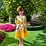 Katie Gardner is registered to the contest to win money with this photo: child, dress, fashion, floral, flowers, garden, girl, gloves, grass, greenery, happy, headband, nature, outdoor, plants, portrait, smile, standing, sunlight, yellow