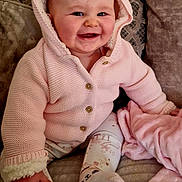 Raya joined the competition — help win amazing prizes! baby, smiling, pink_hoodie, knitwear, couch, blanket, indoors, child, cute, happy, face, sitting, cozy, soft_texture, buttoned_jacket, patterned_pants, sock, infant, warm_clothing, home