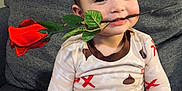 Levu is registered to the contest to win money with this photo: toddler, child, rose, pajamas, smile, face, sitting, couch, indoor, cute, person, leaf, patterned_clothing, happy, young_child, hand, plant, green, red, cozy