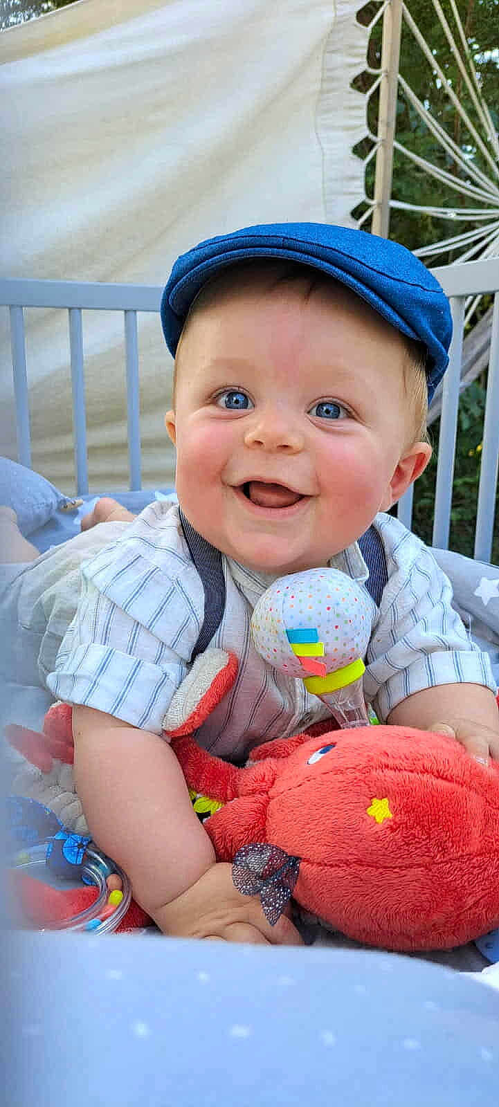 Tennessy a rejoint le concours — aidez-le/la à gagner de superbes lots ! baby, blue_eyes, cap, cheeky_grin, clothing, colorful_toy, crib, cute, expression, face, happy, infant, indoors, looking_at_camera, plush_toy, smile, soft_toys, sitting, toy, young_child