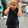 Leo participe au concours pour gagner de l'argent avec cette photo : toddler, child, headphones, red_cap, black_shirt, backpack, indoor, public_space, people, walking, floor, smiling, blond_hair, casual_clothing, waiting_area, modern, blurred_background, happy, cute, music
