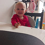 Hortense a rejoint le concours — aidez-le/la à gagner de superbes lots ! toddler, child, smiling, red_clothing, highchair, table, snack, indoor, home, photographs, toy, chair, face, happy, baby, person, furniture, light, background, cute
