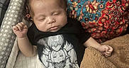 Arthur is registered to the contest to win money with this photo: baby, infant, sleeping, portrait, indoors, blanket, bedding, rug, carpet, black_shirt, anime_shirt, patterned_background, cozy, peaceful, resting, closed_eyes, hands, arms, textile, photography