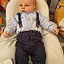 baby, infant, clothing, suspenders, pants, shirt, blanket, cushion, pillow, indoor, person, child, cute, lying_down, comfortable, soft_texture, home, resting, young, fashion