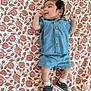 baby, infant, denim_clothing, shorts, shirt, shoes, socks, floral_pattern, blanket, lying_down, smile, face, cute, small_hands, indoor, child, happy, portrait, casual, comfortable