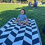 toddler, child, blanket, grass, outdoor, park, toy, laughing, happy, person, summer, nature, greenery, casual_clothing, shorts, tshirt, barefoot, sunlight, trees, recreation