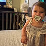Cienna joined the competition — help win amazing prizes! bed, blanket, cable, child, clothing, crib, dress, fan, furniture, hand, happy, head, indoors, pacifier, person, room, smile, standing, television, toddler
