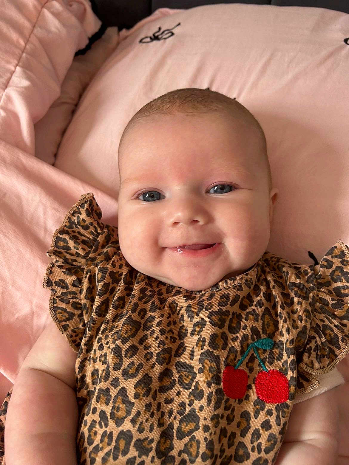 Freya is registered to the contest to win money with this photo: baby, smiling, infant, face, leopard_print, clothing, cute, cheeks, blanket, pink, happy, portrait, child, person, closeup, soft, lying_down, cherry_patch, apparel, adorable