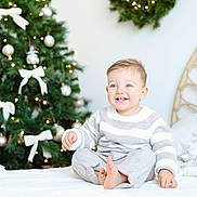 Sasha participe au concours pour gagner de l'argent avec cette photo : bed, blue_eyes, child, christmas_tree, cozy, cute, decorations, festive, happy, holiday_decor, holiday_lighting, home, indoor, portrait, seasonal, smile, striped_sweater, toddler, white_bedspread, wreath