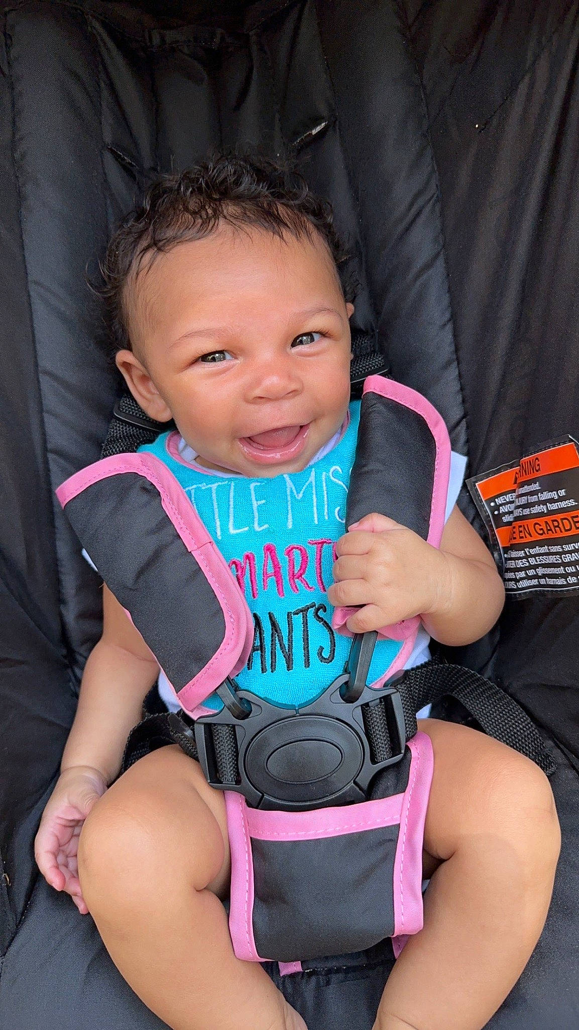 Annalise joined the competition — help win amazing prizes! arm, baby_carriage, baby_toddler_clothing, chair, cheek, comfort, eye, face, facial_expression, finger, fun, happy, human, leg, mouth, person, pink, seat_belt, skin, smile