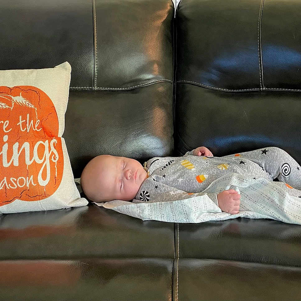 Jerry is registered to the contest to win money with this photo: baby, baby_sleeping, baby_toddler_clothing, bedding, bedroom, bedtime, comfort, couch, flooring, linens, orange, pillow, rectangle, room, sofa_bed, studio_couch, textile, throw_pillow, toddler, wood