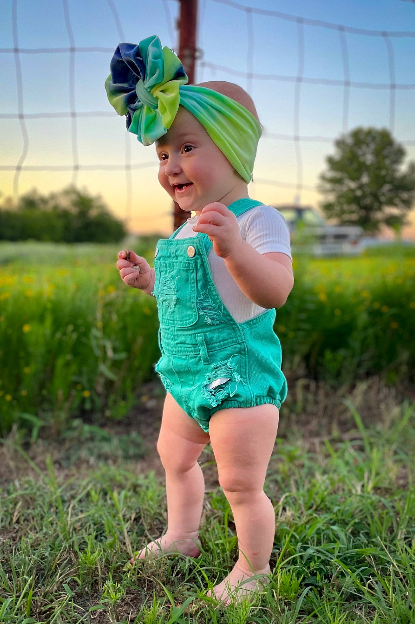 Marley is registered to the contest to win money with this photo: baby_toddler_clothing, eye, face, flash_photography, fun, grass, grassland, green, happy, hat, headwear, leisure, meadow, people_in_nature, person, plant, sky, smile, summer, sunlight