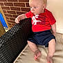 Waylon joined the competition — help win amazing prizes! baby, barefoot, brick_wall, casual_clothing, child, curious, cushion, cute, daylight, infant, navy_shorts, outdoor_chair, person, portrait, red_shirt, relaxed, side_view, sitting, wicker, young_child