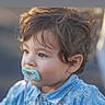 toddler, child, pacifier, blue_shirt, curly_hair, portrait, side_view, outdoor, young_child, innocence, soft_light, baby, cute, face, expression, casual_clothing, person, daylight, closeup, skin