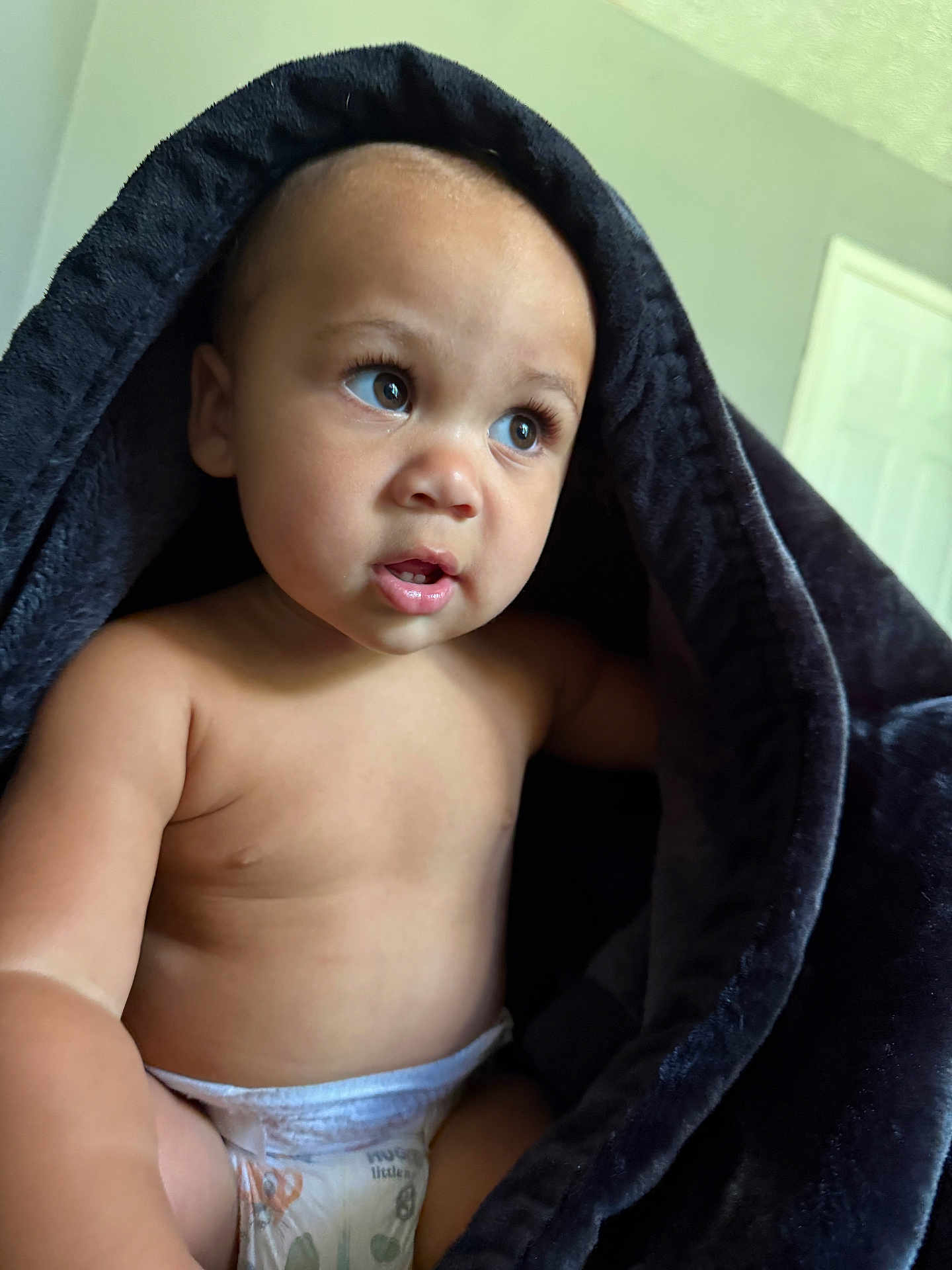 Armani is registered to the contest to win money with this photo: baby, blanket, diaper, indoor, child, curious, face, skin, soft, comfort, expression, infant, person, closeup, head, sitting, young, candid, natural_light, portrait