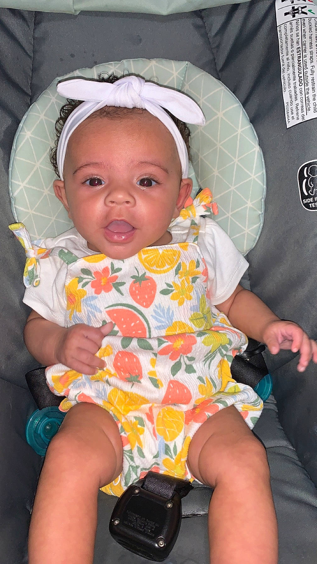 Amara is registered to the contest to win money with this photo: baby, baby_products, baby_toddler_clothing, camera, cheek, child, comfort, finger, fun, happy, human_body, iris, lap, mouth, pattern, person, pink, sitting, skin, thigh