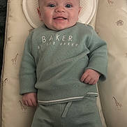 Oliver is registered to the contest to win money with this photo: baby, infant, smiling, lying_down, baby_mat, giraffe_pattern, elephant_pattern, green_clothing, sweater, pants, face, head, hands, cozy, indoor, cute, child, person, happy, soft