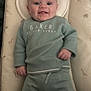 baby, infant, smiling, lying_down, baby_mat, giraffe_pattern, elephant_pattern, green_clothing, sweater, pants, face, head, hands, cozy, indoor, cute, child, person, happy, soft