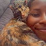cat, calico_cat, person, face, smile, couch, pillow, indoor, close_up, snuggle, pet, animal, feline, cozy, relaxation, companion, friendship, warmth, resting, cute