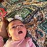 baby, child, infant, portrait, lying_down, bed, bedspread, bow, pink_clothing, onesie, face, eyes, open_mouth, smiling, indoor, home, textile, patterned_background, close_up, cute