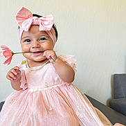 Adelina is registered to the contest to win money with this photo: baby, child, pink_dress, headband, bow, flower, smile, happy, cute, indoors, portrait, hand, pearl_necklace, person, infant, celebration, fashion, toddler, adorable, playful