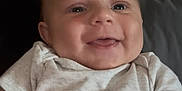 Dexter is registered to the contest to win money with this photo: baby, smile, face, infant, child, onesie, happy, cute, portrait, closeup, chubby_cheeks, sitting, skin, person, indoors, young_child, head, mouth, eyes, light
