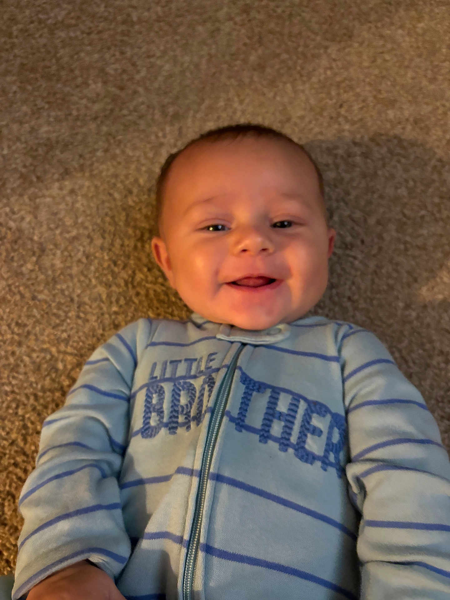 Dexter is registered to the contest to win money with this photo: baby, child, smile, happy, onesie, blue_clothing, striped_clothing, floor, carpet, portrait, infant, face, cute, lying_down, young_child, person, indoors, childhood, joy, toddler