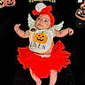 adorable, baby, bib, black_background, celebration, child, costume, cute, decorations, festive, halloween, headband, holiday, holiday_clothing, holiday_theme, infant, infant_clothing, lying_down, pumpkin, red_tutu