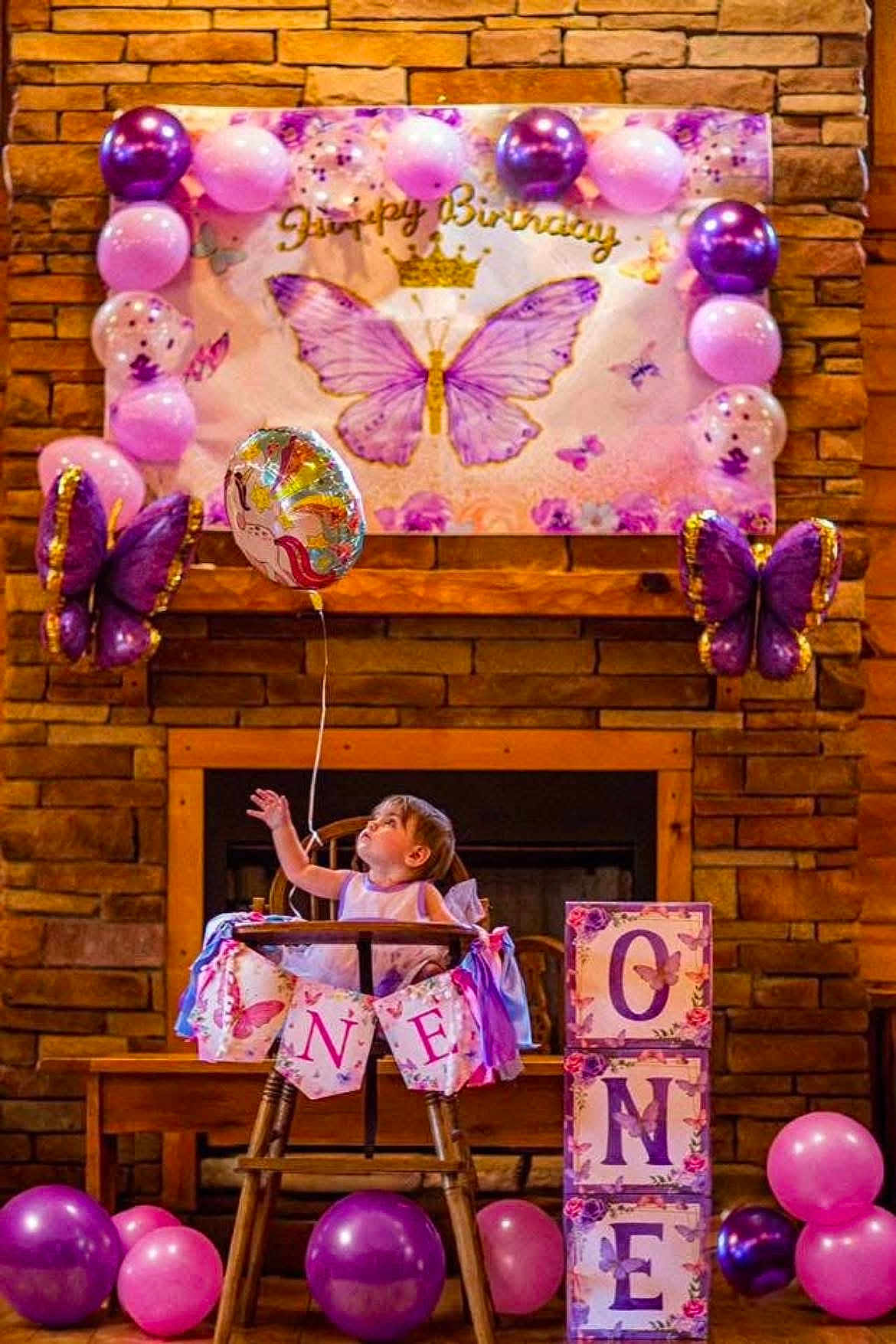 Miley is registered to the contest to win money with this photo: toddler, child, high_chair, balloon, birthday, party, decoration, purple, pink, butterfly, banner, unicorn, celebration, wooden, dress, festive, indoor, blocks, smiling, happy