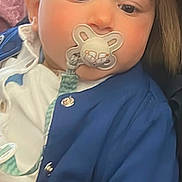 Joulene a rejoint le concours — aidez-le/la à gagner de superbes lots ! baby, pacifier, blue_jacket, child, face, infant, person, clothing, holding, adult_partial, portrait, closeup, indoors, cute, looking_away, soft_background, human, young_child, casual, warm_clothing