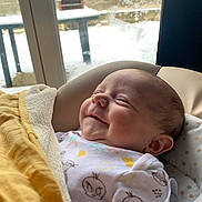 Emma participe au concours pour gagner de l'argent avec cette photo : baby, blanket, child, clothing, cozy, cute, expression, face, furniture, happy, indoors, infant, portrait, resting, seat, smile, snow, warm, window, winter