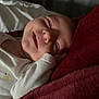 Emma a rejoint le concours — aidez-le/la à gagner de superbes lots ! baby, sleeping, smiling, infant, blanket, white_clothing, cozy, face, peaceful, resting, soft_texture, red_blanket, hand, indoors, portrait, newborn, cute, relaxed, closeup, child