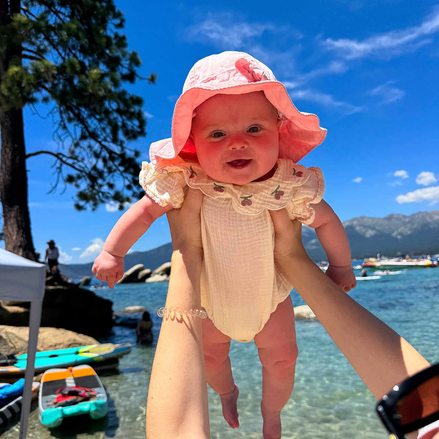Leia joined the competition — help win amazing prizes! baby, child, sunhat, water, lake, mountains, sky, clouds, tree, paddleboard, person, holding, summer, outdoor, nature, sunlight, happy, portrait, arm, beach
