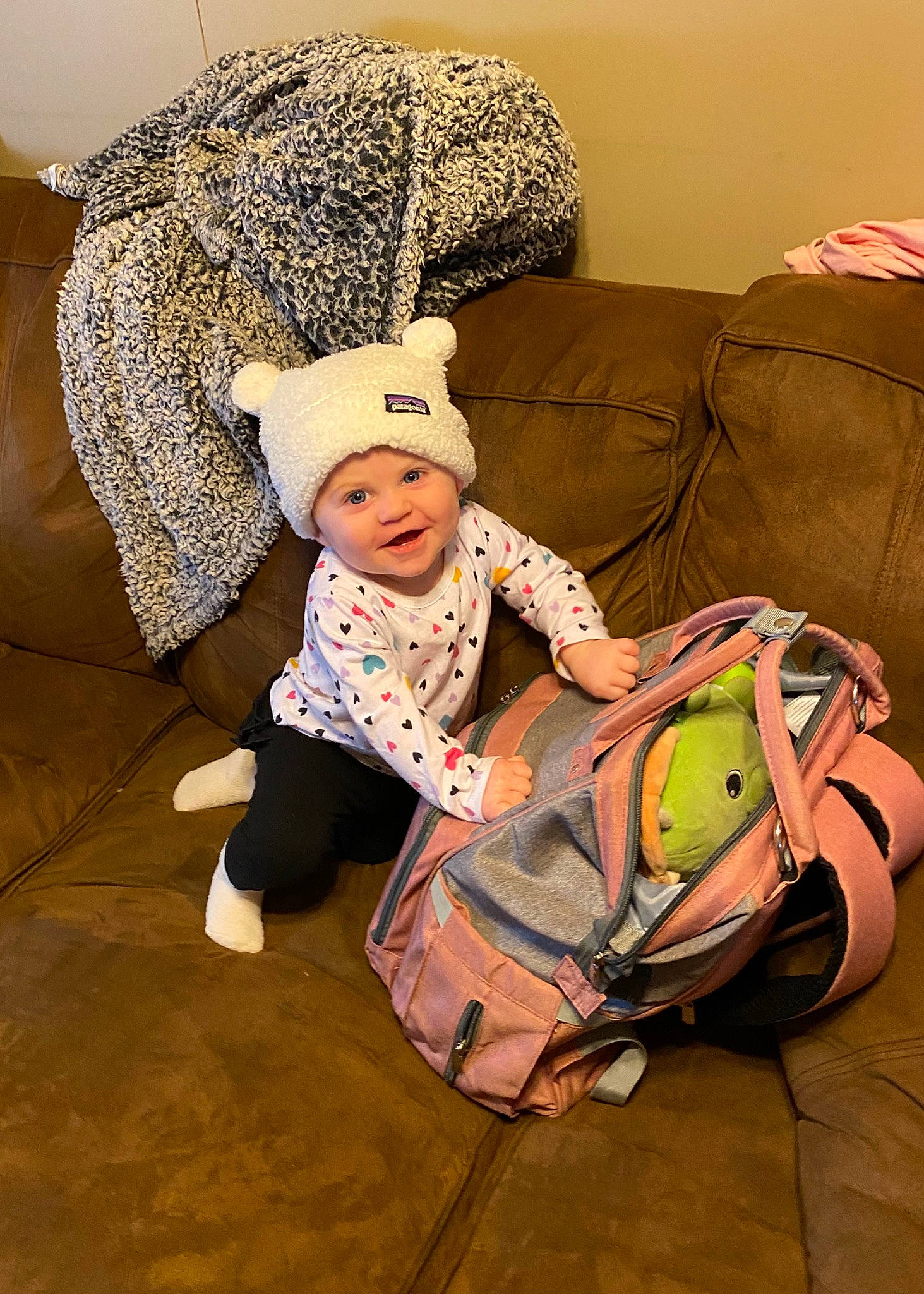 Ryleigh is registered to the contest to win money with this photo: baby, baby_toddler_clothing, bag, beanie, cap, child, comfort, couch, fashion_accessory, flooring, foot, fun, headwear, knit_cap, linens, luggage_and_bags, pattern, person, room, sitting