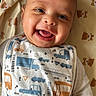 baby, baby_garment, bib, blanket, child, clothing, cute, eyes, face, hand, happy, indoors, infant, lying_down, mouth, person, portrait, skin, smile, teddy_bear