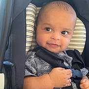 Ibrahim is registered to the contest to win money with this photo: baby, infant, car_seat, child, smile, seatbelt, safety, clothing, patterned_outfit, cute, hands, looking_away, indoor, portrait, head_support, happy, young_child, seat, black_straps, small_person