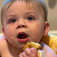 Bennett is registered to the contest to win money with this photo: baby, child, face, food, hand, snack, messy, closeup, blue_eyes, skin, mouth_open, fingers, expression, indoors, curly_hair, cheek, cute, toddler, eating, feeding_time