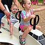 Amelia joined the competition — help win amazing prizes! child, baby, playground, playground_equipment, play, ride, space_shuttle, smile, person, outdoor, sand, gravel, summer_clothing, toddler, holding, fun, colorful, shoes, shorts, family