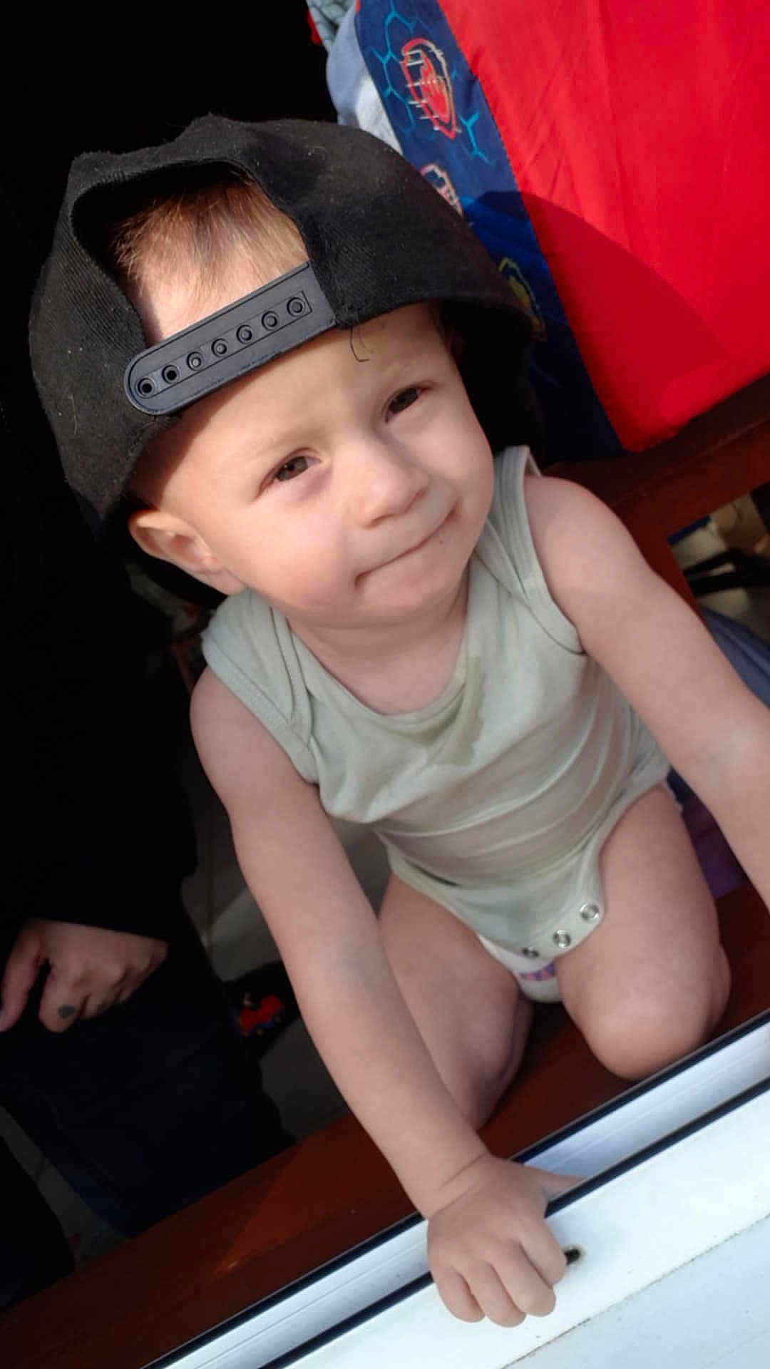 Jukka participe au concours pour gagner de l'argent avec cette photo : toddler, child, cap, backward_cap, onesie, indoor, curious, face, hand, tattoo, blanket, colorful, furniture, window, leaning, expression, baby, skin, person, portrait