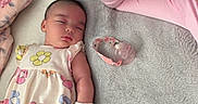 Lyanna Rose is registered to the contest to win money with this photo: baby, sleeping, adult, woman, blanket, pacifier, floral_outfit, resting, indoor, cozy, person, face, head, pink, skin, comfort, toddler, family, mother, care