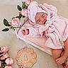 baby, sleeping, pink, robe, towel, bed, flower, roses, wooden_plaque, month_marker, infant, soft_texture, pastel_colors, cute, peaceful, newborn, decor, portrait, indoors, resting